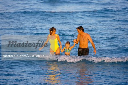 Family in Swimwear, Walking in Water at Beach