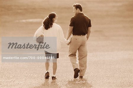 father and daughter holding hands walking