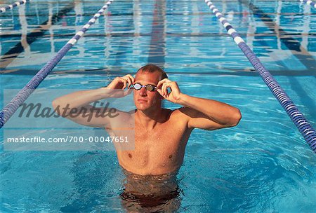 Man in Swimming Pool, Adjusting Goggles