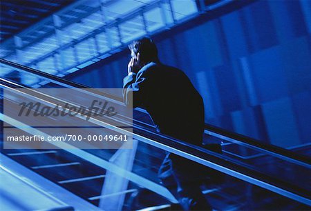 Businessman Using Cell Phone on Escalator