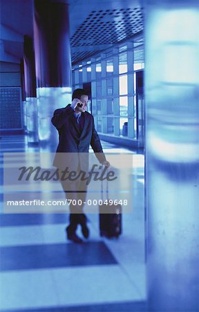 Businessman with Luggage Using Cell Phone in Terminal