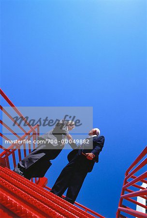 Mature Businessmen Shaking Hands On Stairs Outdoors