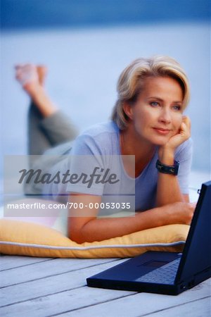 Mature Woman Lying on Deck with Laptop Computer