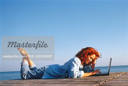 Woman Lying on Dock, Using Laptop Computer