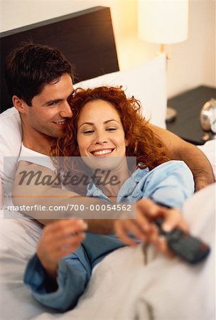 Couple in Bed, Fighting over Television Remote Control