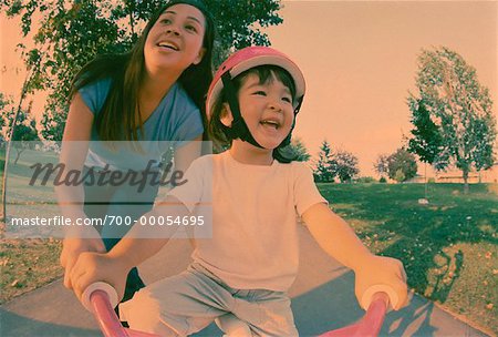 Mother Helping Daughter Ride Bicycle in Park