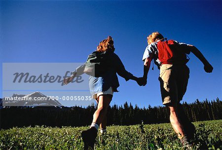 Back View of Couple Hiking Through Field