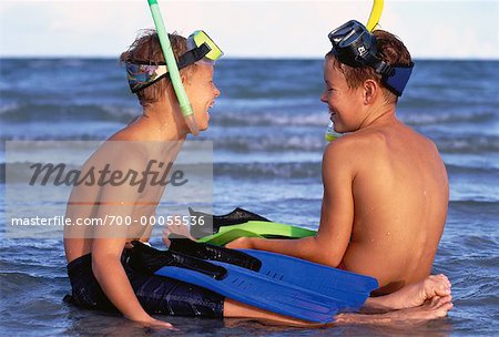 Two Boys in Swimwear, Sitting on Beach with Snorkeling Gear