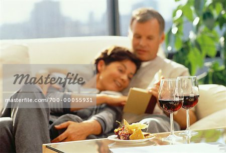 Mature Couple Sitting on Sofa With Wine and Cheese on Table