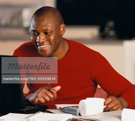 Man Sitting at Table Using Laptop Computer