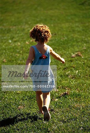 Back View of Girl Walking through Field - Stock Photo - Masterfile