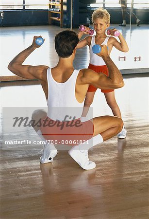 Father and Son Wearing Matching Clothes, Lifting Weights in Gym