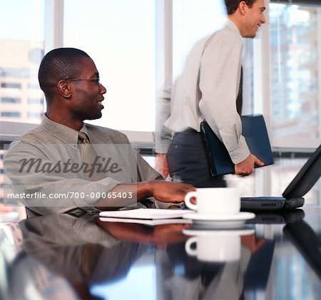 Businessman Sitting at Table Talking to Businessman Walking