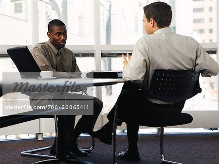 Two Businessmen Sitting at Table Talking - Stock Photo