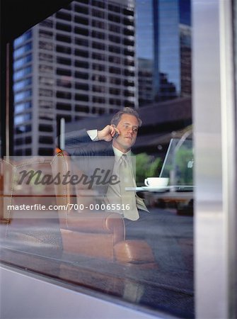 View of Businessman Using Cell Phone through Restaurant Window