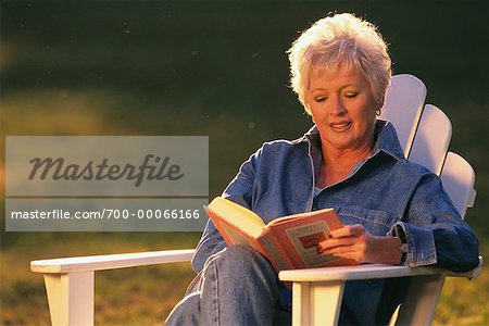 Mature Woman in Adirondack Chair Reading Book Outdoors