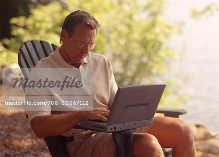 Man Sitting in Chair, Using Laptop Computer near Lake