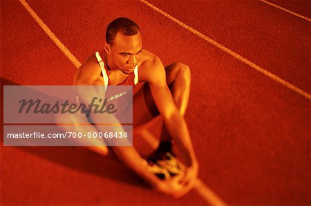 Male Athlete Sitting on Track Holding Feet