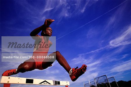 Female Athlete Jumping over Hurdles
