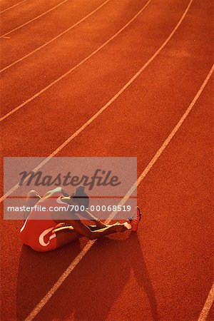 Back View of Female Athlete Sitting on Track, Stretching Legs
