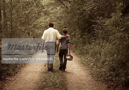 https://image1.masterfile.com/getImage/700-00068631em-back-view-of-father-and-son-on-dirt-road-with-fishing-gear-stock.jpg