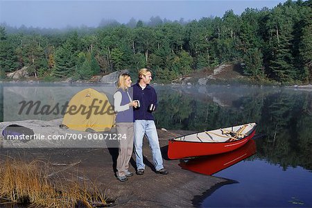 Couple Holding Mugs with Tent and Canoe near Lake Haliburton, Ontario, Canada