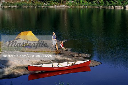 Couple on Rocks with Tent and Canoe near Lake Haliburton, Ontario, Canada
