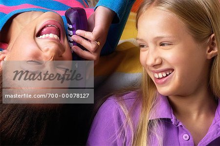 Two Girls Using Cordless Phone Laughing in Bedroom