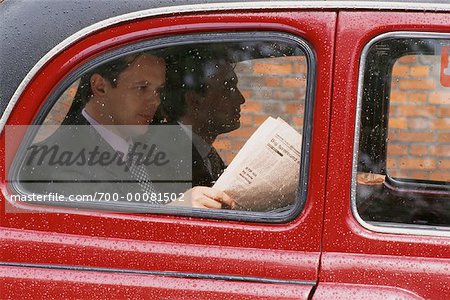 Businessmen Reading Newspaper in Taxi