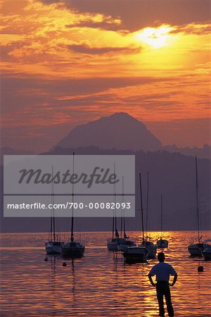 Back View of Man Standing on Beach with View of Boats in Harbor, Guanabara Bay Rio de Janeiro, Brazil