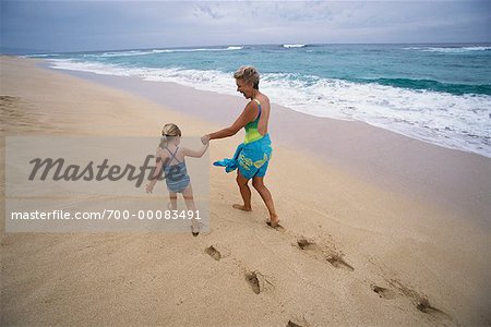 Grandmother and Granddaughter Walking on Beach, Holding Hands