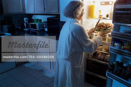 Mature Woman Standing at Fridge Having Chicken as Midnight Snack