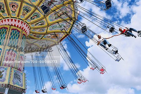 Couple On Swing Ride At Amusement Park Stock Photo