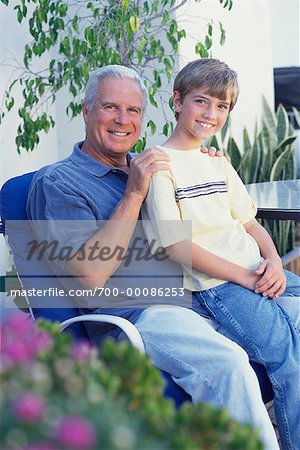 Portrait of Grandfather and Grandson Sitting on Chair Outdoors