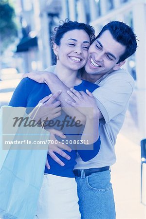 Couple Embracing and Holding Shopping Bags Outdoors