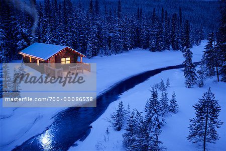 Log Cabin by Stream in Winter At Dusk