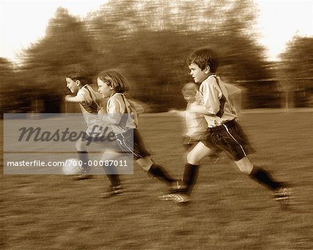 Blurred View of Children Running in Field, Playing Soccer