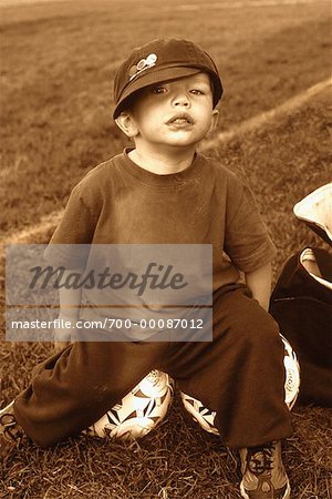 Portrait of Boy Sitting on Soccer Ball Outdoors