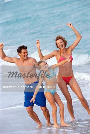 Young Parents Dancing with Daughter on Beach