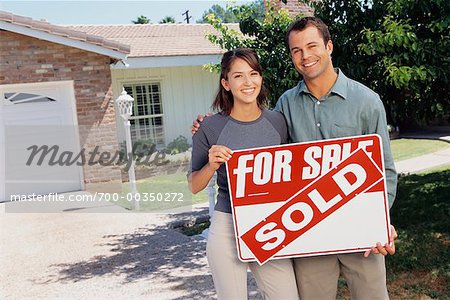 Couple Holding Sold Sign