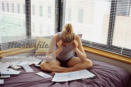 Woman Studying Bills on Bed