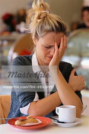 Woman Holding Head in Restaurant