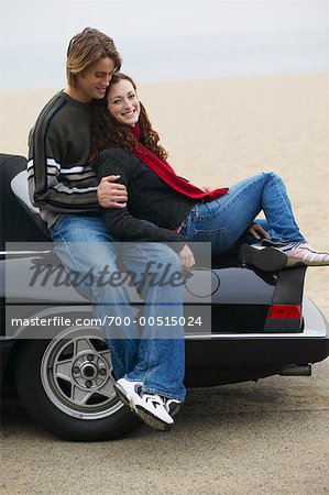 Couple Sitting On Back of Car