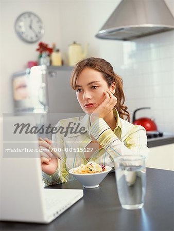 Teenager Eating Cereal While Looking at Computer