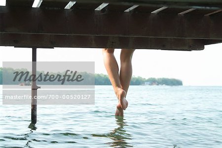 Woman Sitting on Dock with Feet In Water