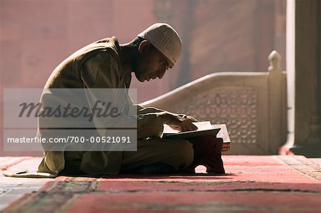 Person Reading Koran in Jama Masjid Mosque, Delhi, India