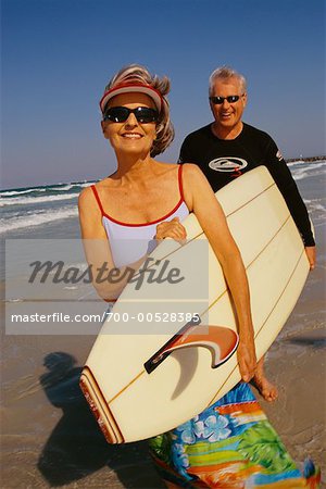 Couple Carrying Surfboard on Beach