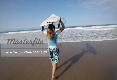 Woman Running on Beach with Surfboard