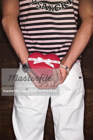 Man Holding Heart-Shaped Box Behind Back