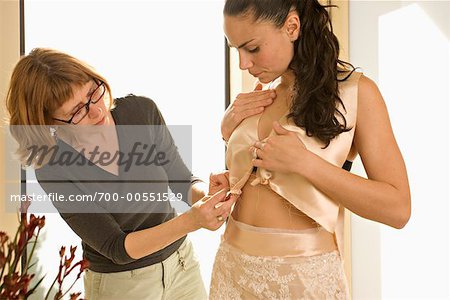 Seamstress Helping Woman Try On Wedding Dress